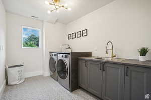 Washroom featuring cabinets, independent washer and dryer, an inviting chandelier, and sink