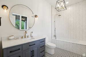 Full bathroom featuring toilet, vanity, tile patterned floors, and tiled shower / bath