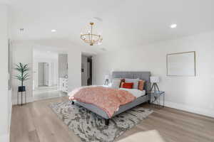 Bedroom with a chandelier, vaulted ceiling, and light hardwood / wood-style floors