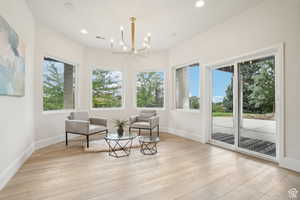 Living area featuring light wood-type flooring, plenty of natural light, and a notable chandelier