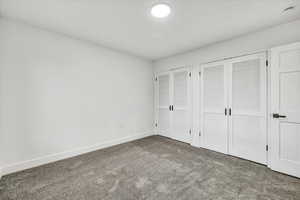 Unfurnished bedroom featuring carpet flooring and multiple closets