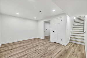 Basement with light hardwood / wood-style floors