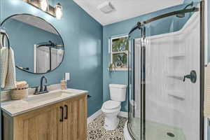 Bathroom with tile patterned flooring, vanity, toilet, and walk in shower