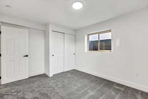 Unfurnished bedroom featuring dark colored carpet and a closet