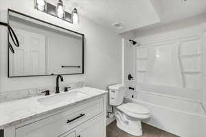 Full bathroom featuring vanity, a textured ceiling, bathing tub / shower combination, tile patterned flooring, and toilet