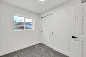 Unfurnished bedroom featuring a closet and dark colored carpet