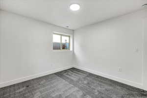 Empty room featuring dark colored carpet