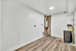 Spare room with water heater and light hardwood / wood-style flooring