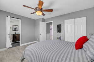 Bedroom with ensuite bathroom, ceiling fan, a closet, and light hardwood / wood-style flooring