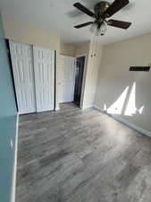 Unfurnished bedroom featuring ceiling fan, wood-type flooring, and a closet