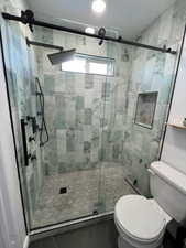 Bathroom featuring tile patterned floors, toilet, and an enclosed shower