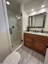 Bathroom with vanity, toilet, and a shower with shower door