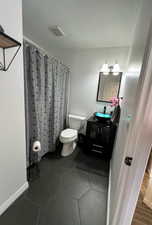 Bathroom with a textured ceiling, vanity, toilet, and curtained shower