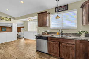 Kitchen with stainless steel dishwasher, decorative light fixtures, dark brown cabinets, and sink