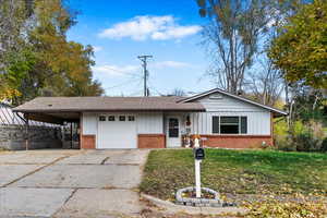 Ranch-style home with a front lawn, a garage, and a carport