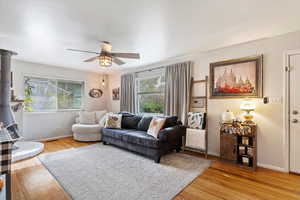 Living room with light wood-type flooring, a wood stove, and a wealth of natural light