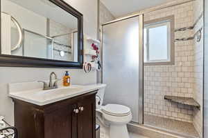 Bathroom featuring toilet, vanity, tile patterned floors, and a shower with door