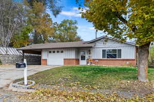 Single story home featuring a front lawn, a carport, and a garage