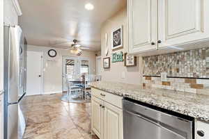 Kitchen with light stone countertops, french doors, ceiling fan, decorative backsplash, and appliances with stainless steel finishes