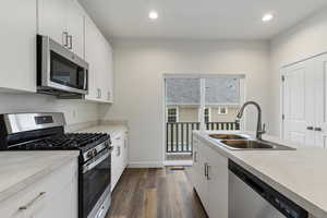 Kitchen featuring white cabinets, appliances with stainless steel finishes, dark hardwood / wood-style flooring, and sink