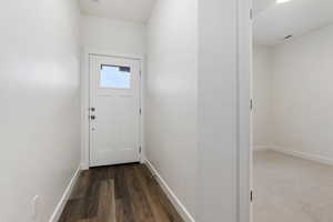 Doorway with dark hardwood / wood-style floors