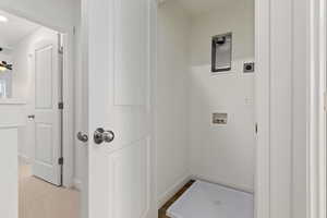 Clothes washing area with hookup for a washing machine, light colored carpet, and electric dryer hookup