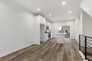 Kitchen with white cabinets, a center island, dark wood-type flooring, and appliances with stainless steel finishes