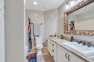 Full bathroom with tile patterned floors, vanity, toilet, and shower / bath combination with curtain