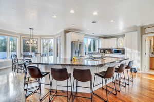 Kitchen with white cabinetry, appliances with stainless steel finishes, a spacious island, and a breakfast bar