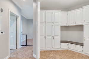 Mudroom with light tile patterned floors and ornamental molding