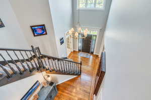 Entryway with a high ceiling, a healthy amount of sunlight, light wood-type flooring, and a notable chandelier