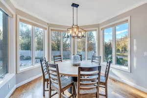 Dining room featuring light wood-type flooring, a healthy amount of sunlight, and crown molding