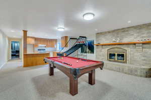 Recreation room with a fireplace, a textured ceiling, light carpet, and pool table