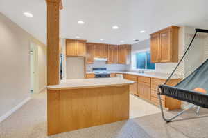 Kitchen with kitchen peninsula, appliances with stainless steel finishes, sink, and light carpet