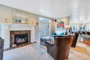 Living room with hardwood / wood-style floors, a premium fireplace, and crown molding