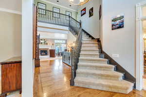 Staircase with hardwood / wood-style floors, a chandelier, and crown molding