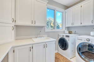 Washroom featuring cabinets, sink, and washer and clothes dryer