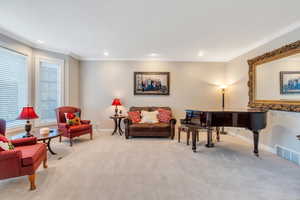 Living area featuring light carpet and crown molding