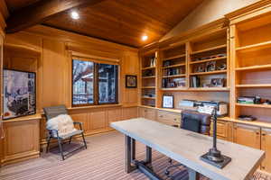 Home office with wooden walls, wooden ceiling, vaulted ceiling, and light carpet