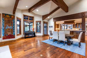 Dining space featuring wood-type flooring, high vaulted ceiling, and beam ceiling