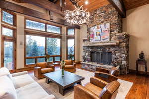 Living room featuring a towering ceiling, wood ceiling, wood-type flooring, beam ceiling, and a fireplace