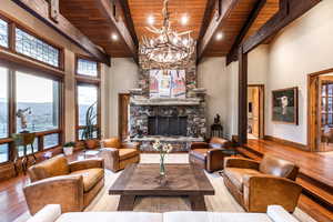 Living room featuring beam ceiling, a fireplace, wood ceiling, and light hardwood / wood-style floors