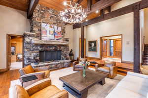 Living room with a fireplace, high vaulted ceiling, wood ceiling, and light wood-type flooring