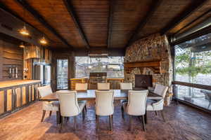 Dining space featuring vaulted ceiling with beams, wood walls, a fireplace, and wood ceiling