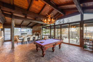 Game room with a stone fireplace, high vaulted ceiling, beamed ceiling, billiards, and wood ceiling