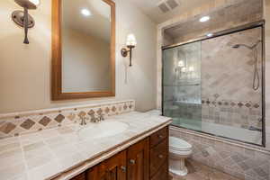 Full bathroom with tile patterned flooring, vanity, bath / shower combo with glass door, and toilet