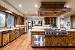 Kitchen with appliances with stainless steel finishes, a tray ceiling, sink, light hardwood / wood-style floors, and butcher block counters