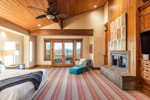 Bedroom featuring ceiling fan, a fireplace, wooden ceiling, and french doors