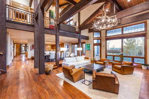 Living room with beam ceiling, high vaulted ceiling, hardwood / wood-style flooring, and an inviting chandelier