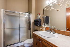 Bathroom with vanity, an enclosed shower, toilet, and an inviting chandelier